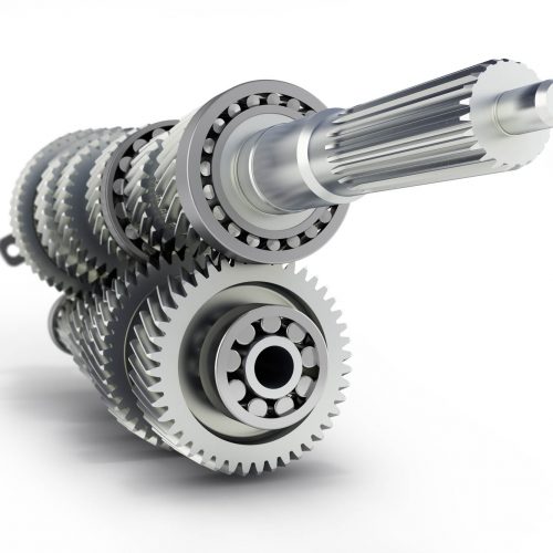 Close-up of a mechanical gear assembly featuring several interlocking metal gears and a central cylindrical shaft. The gears have precision-cut teeth and metal ball bearings, showcasing industrial engineering and machinery components on a white background.